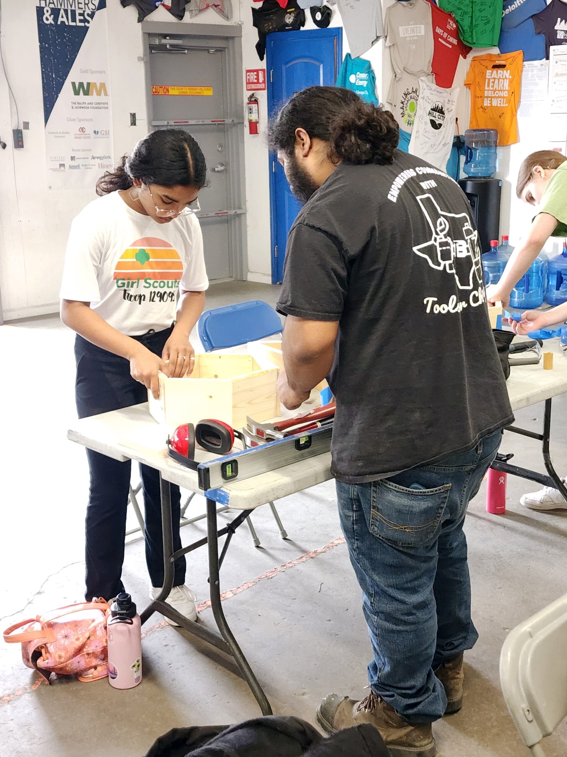 A Houston ToolBank staff member showing a student how to glue wood together at the Tool School